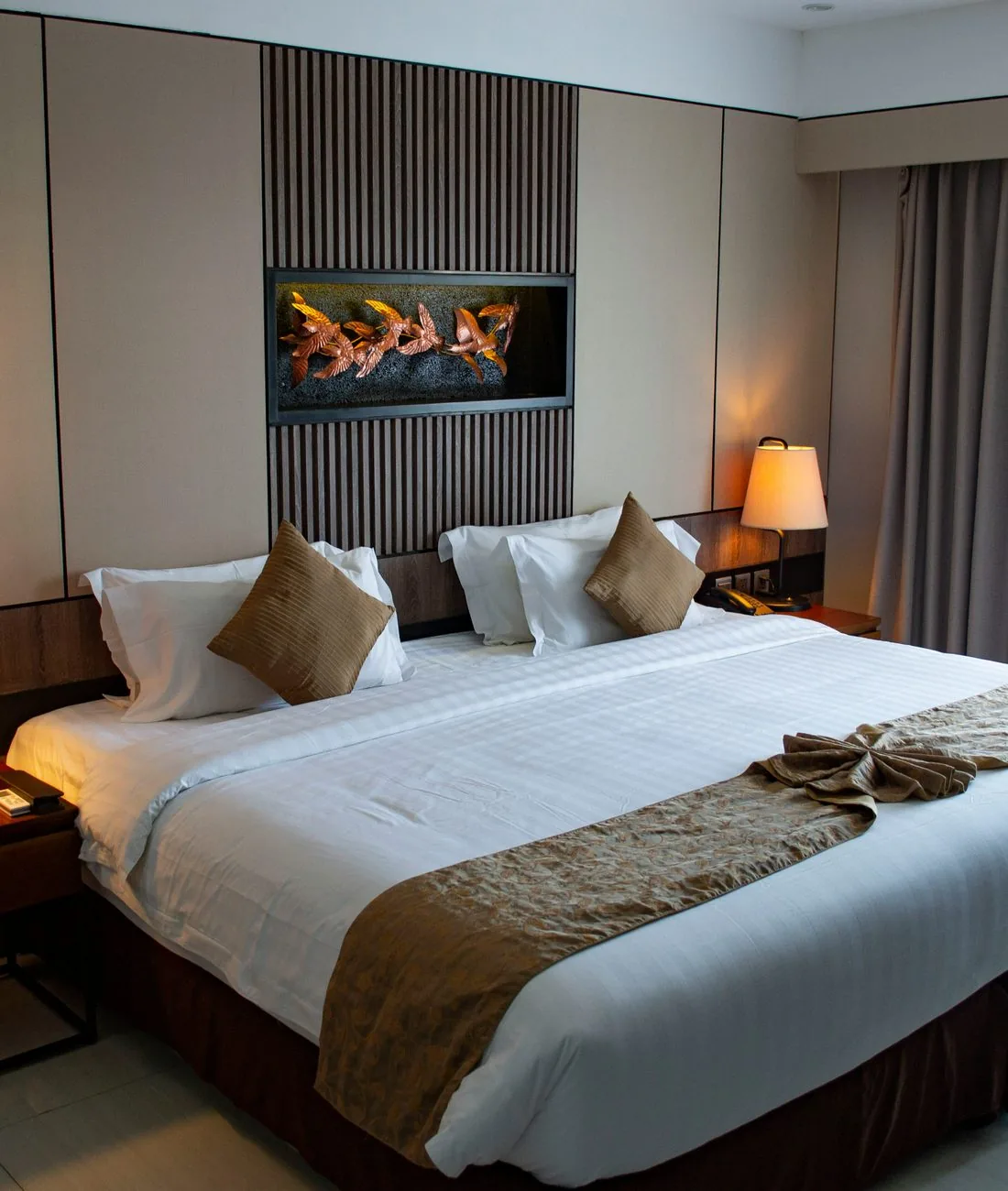 Hotelsuite mit King-Size-Bett, Holzwand und warmem Lampenlicht